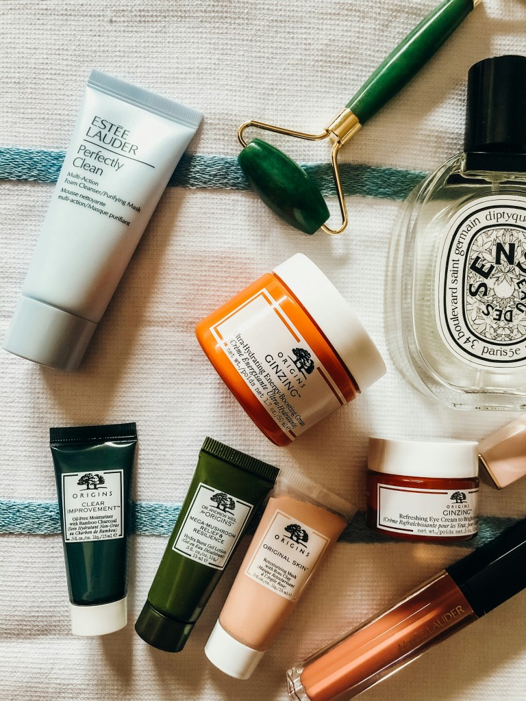 flat lay style image of origins and estee lauder skincare products and diptyque perfume