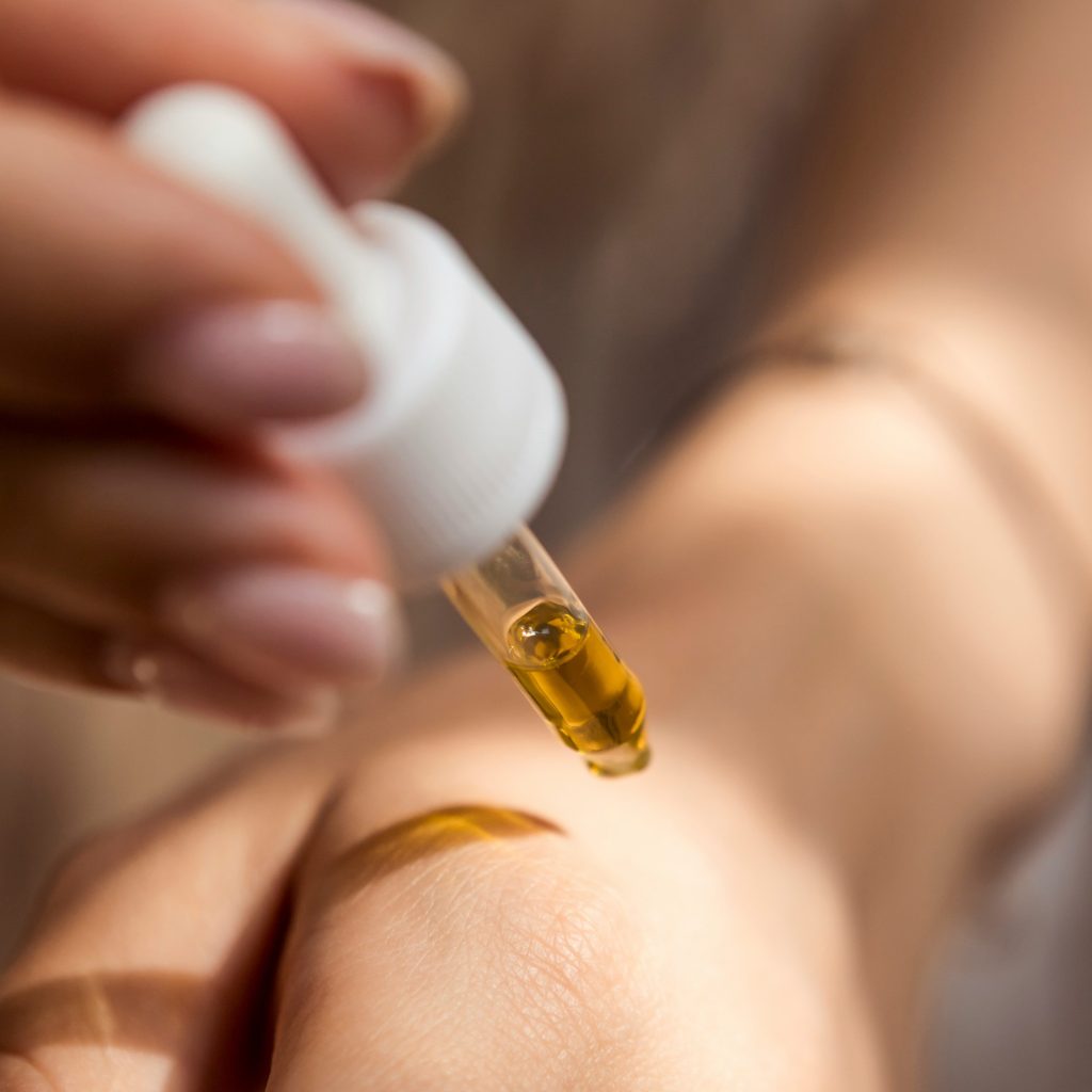 woman applying face oil on the back of hand